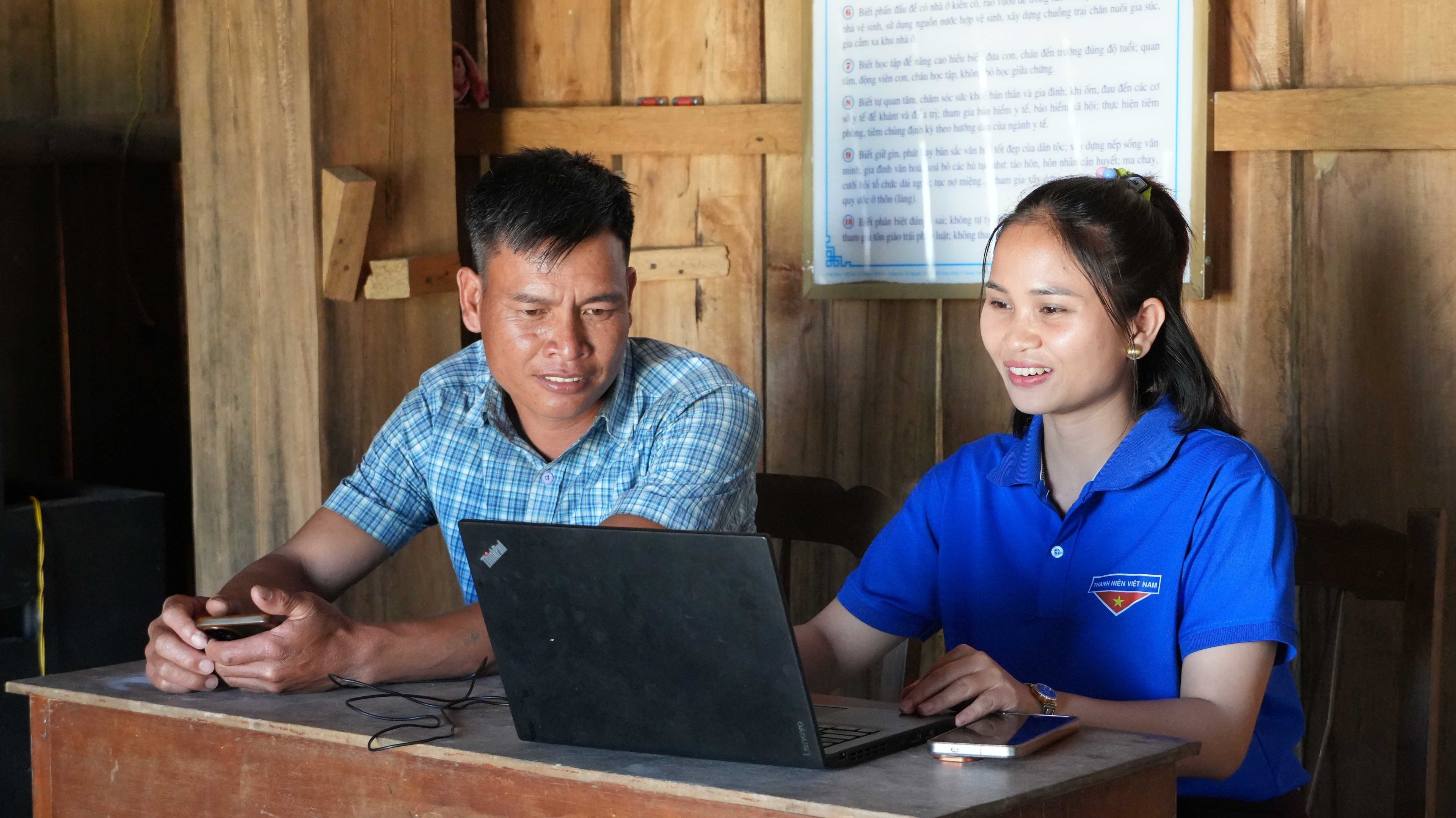 Thành viên Tổ công nghệ số cộng đồng thôn Vi Glơng, xã Kon Plông, tỉnh Quảng Ngãi, hướng dẫn người dân nộp hồ sơ thủ tục hành chính trực tuyến. (Ảnh: Dư Toán/TTXVN)